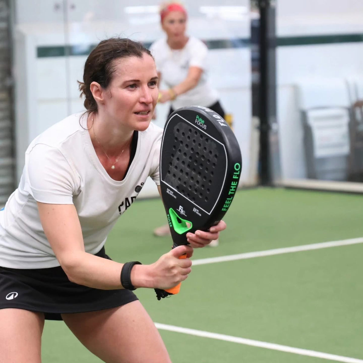 Club player competing with a black and green FLO Pulse Focus padel racket