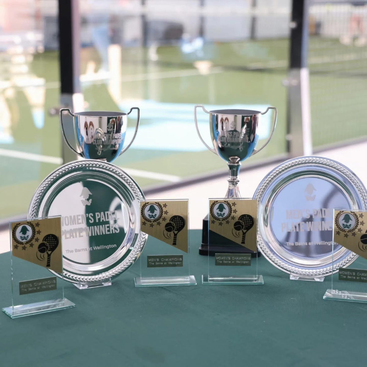 Men’s and women’s padel competition trophies displayed beside the courts at The Barns at Wellington